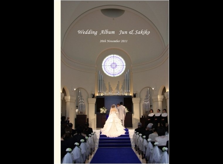 丸く美しいステンドグラスを正面に、祭壇からまっすぐ伸びるロイヤルブルーのバージンロード。1頁目：結婚式アルバム